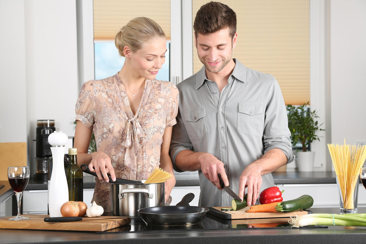Pareja cocinando en casa con utensilios de cocina